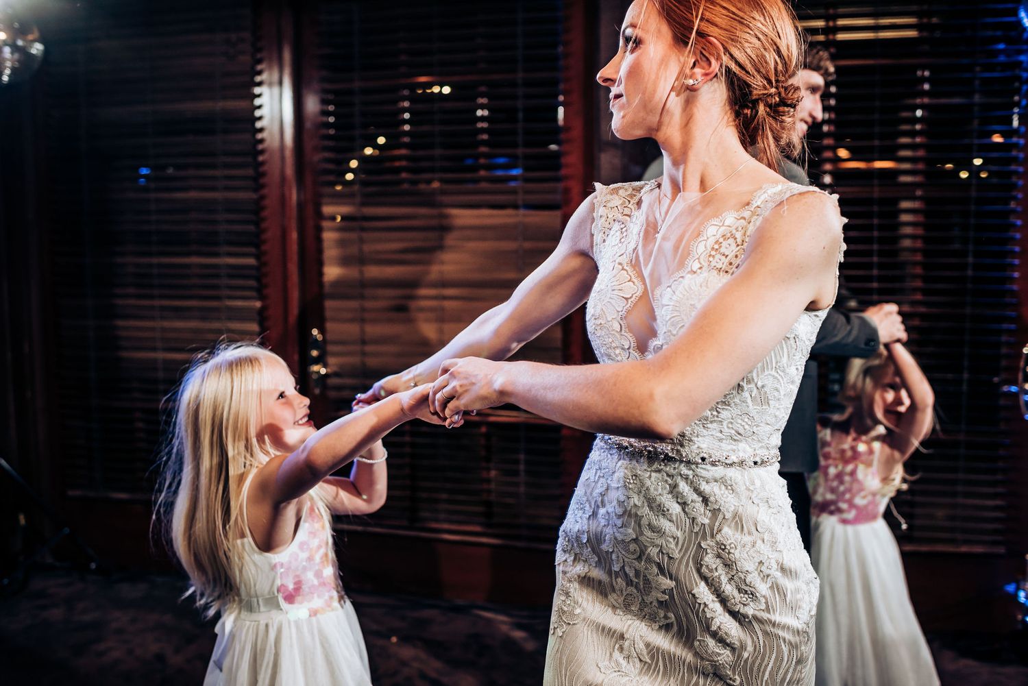 Tender dancing moment between bride and young flower girl at wedding reception.