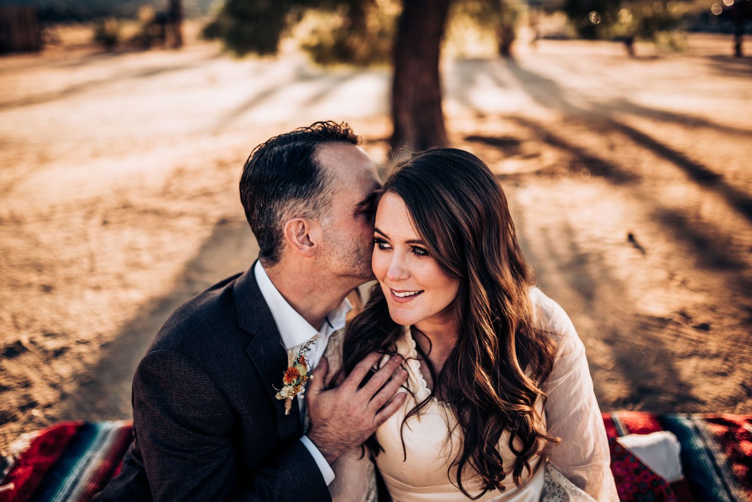 A couple laughs together during their outdoor wedding portrait session at sunset.
