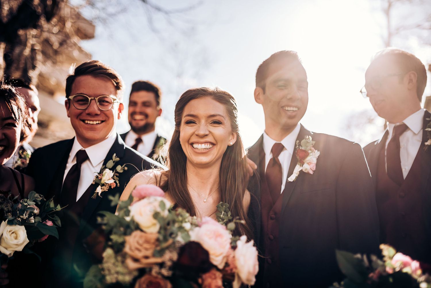 Wedding party sharing genuine laughter and joy during outdoor celebration.