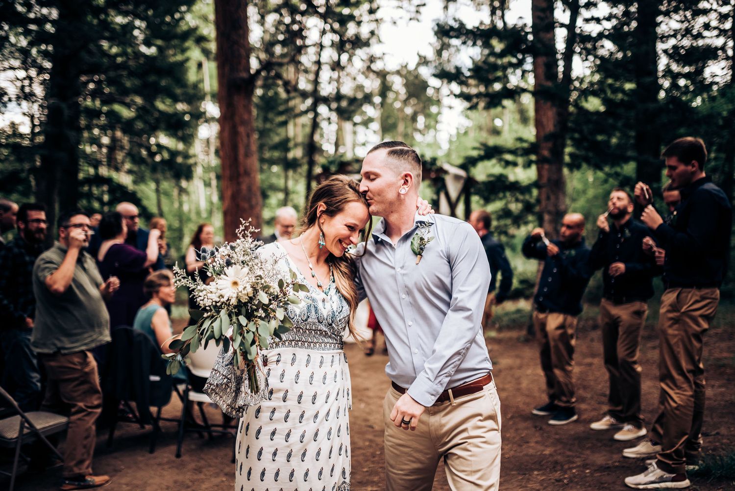 A romantic recessional walk down the aisle in a forest wedding setting.