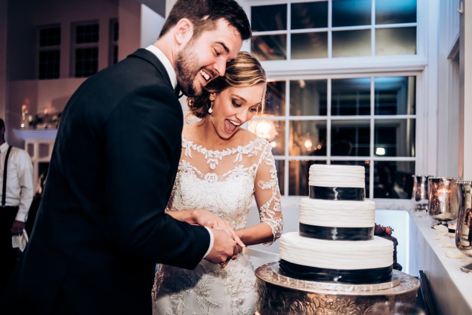 Couple shares intimate moment while cutting their black and white tiered wedding cake.