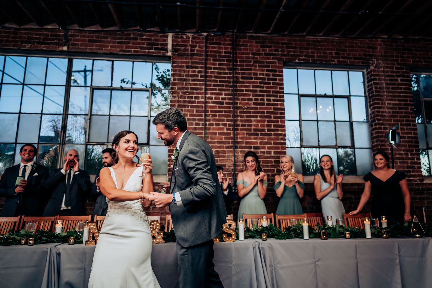 Wedding ceremony in industrial brick venue with guests watching the couple exchange vows.