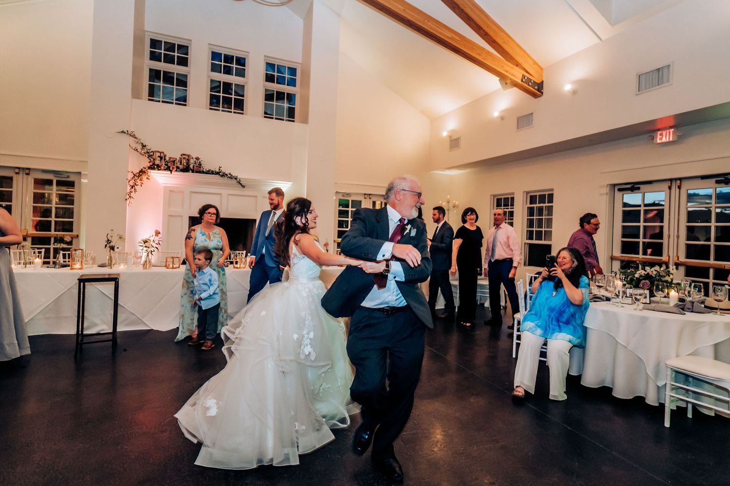Wedding couple sharing their first dance in an elegant reception venue with exposed wooden beams.