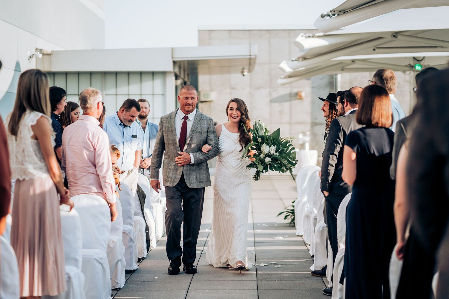 Wedding ceremony on a modern rooftop terrace with white chairs and elegant decor.