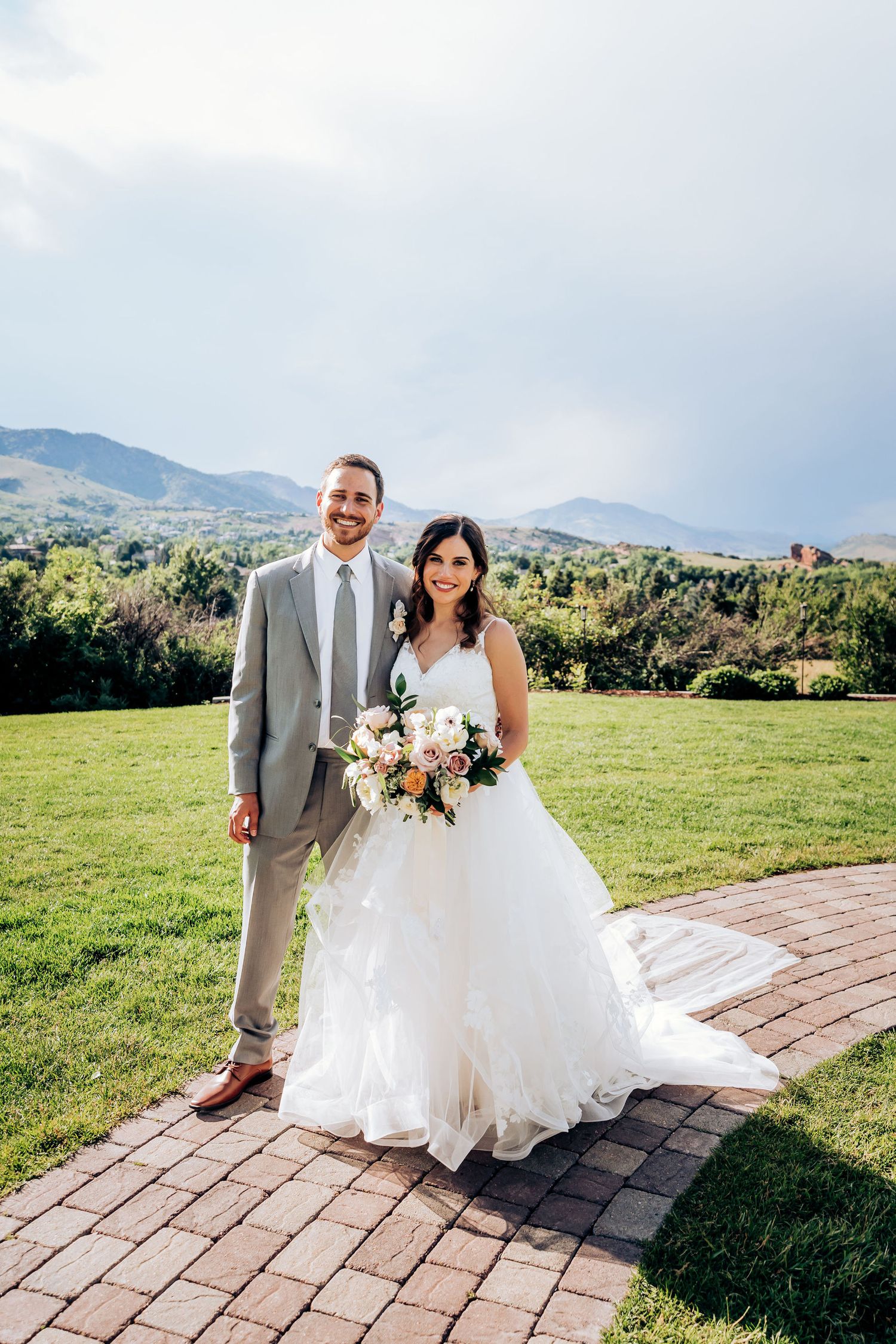 Newlyweds pose on a brick pathway with scenic mountain views on their wedding day.