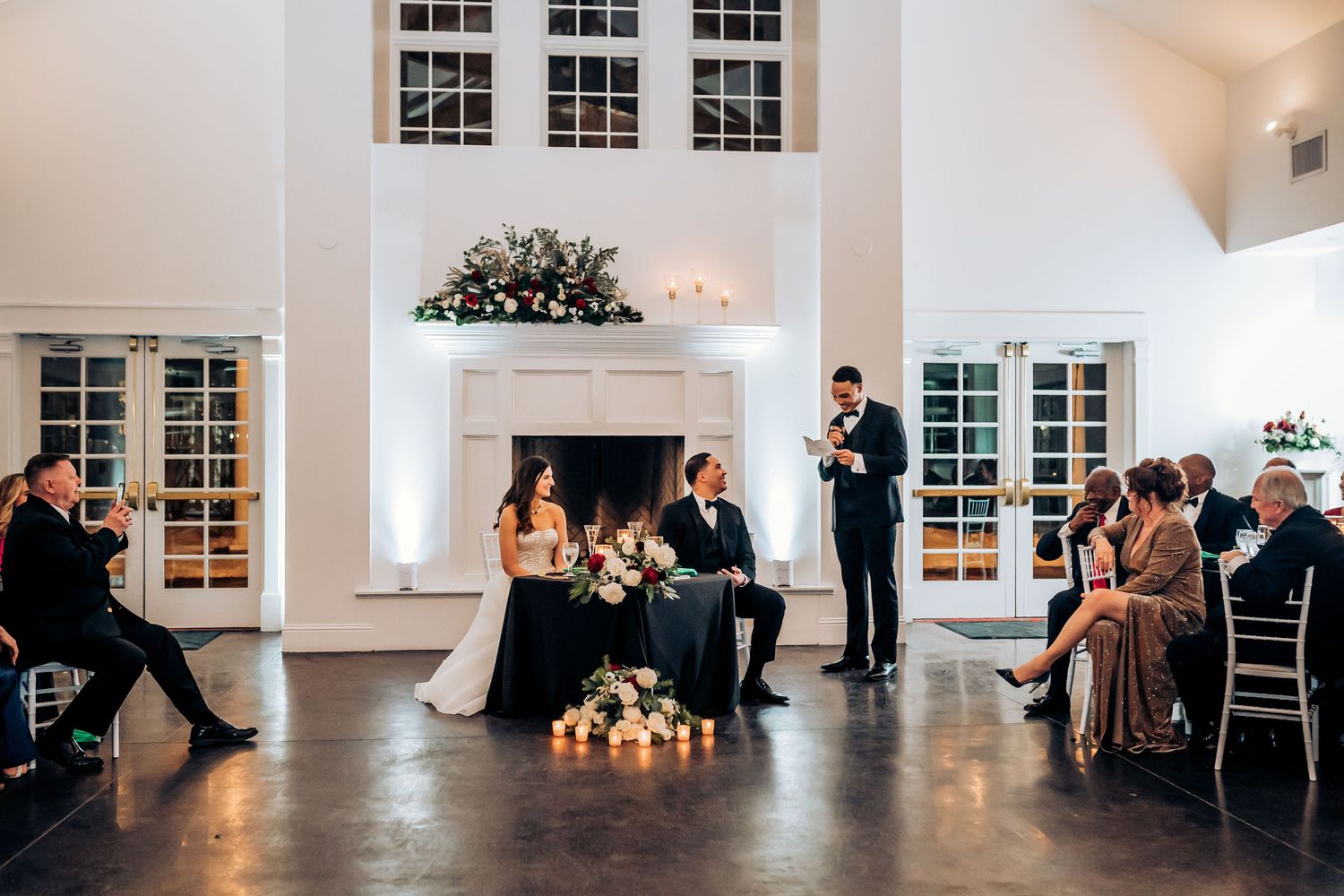 Wedding reception celebration in white room with fireplace and romantic candle lighting.