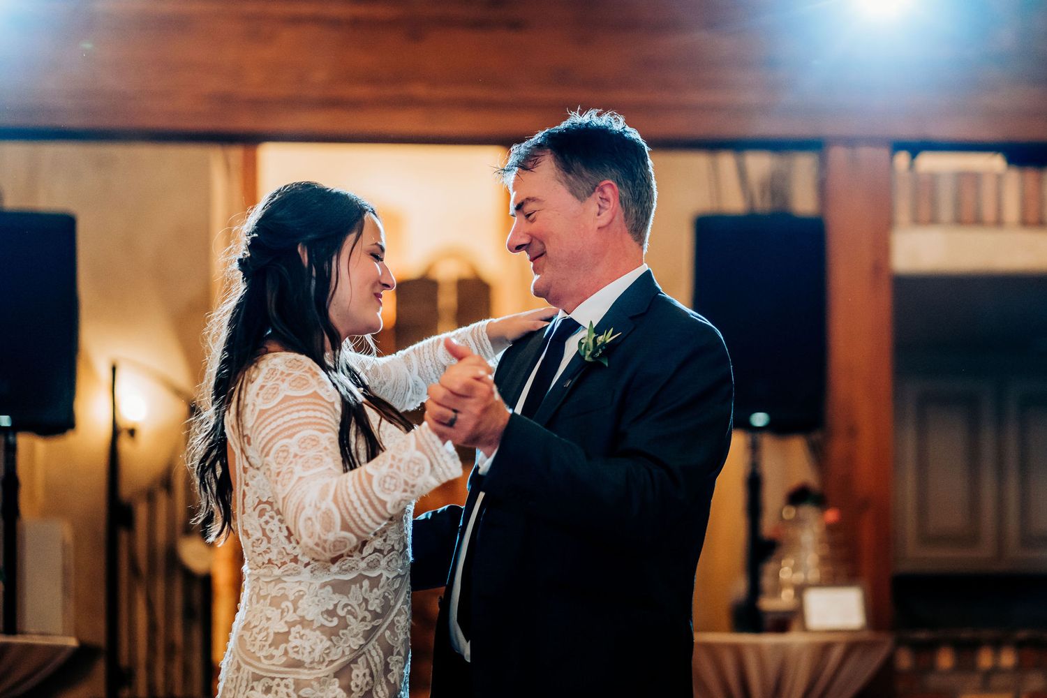 Newlyweds share their first dance together in an intimate venue with warm lighting and rustic wooden decor.
