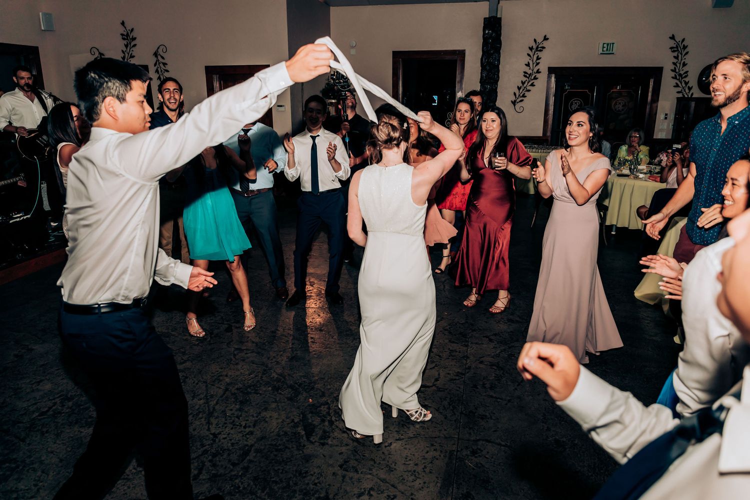 Guests dancing under raised arms creating a tunnel on the reception dance floor.