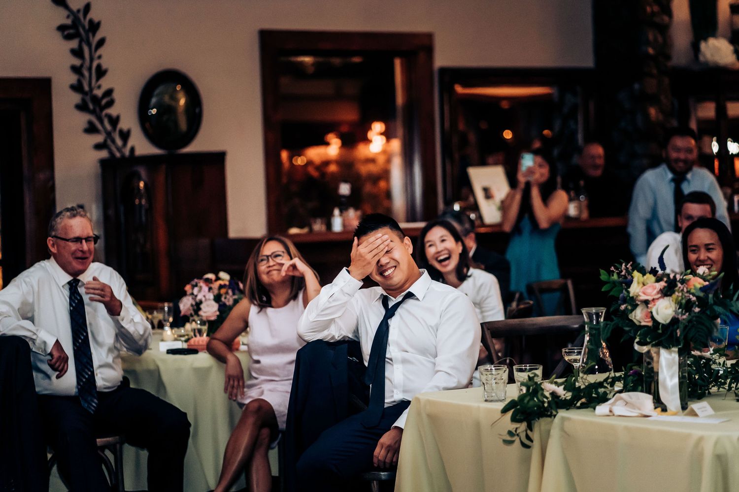 Wedding guests laughing and enjoying themselves at round tables during the reception.