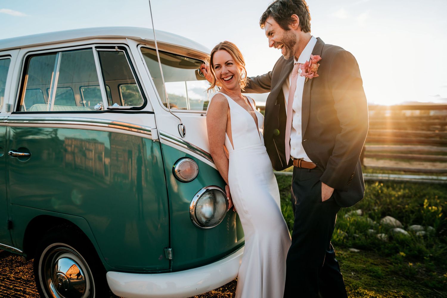 A couple stands beside a retro green VW bus during a scenic sunset photoshoot.