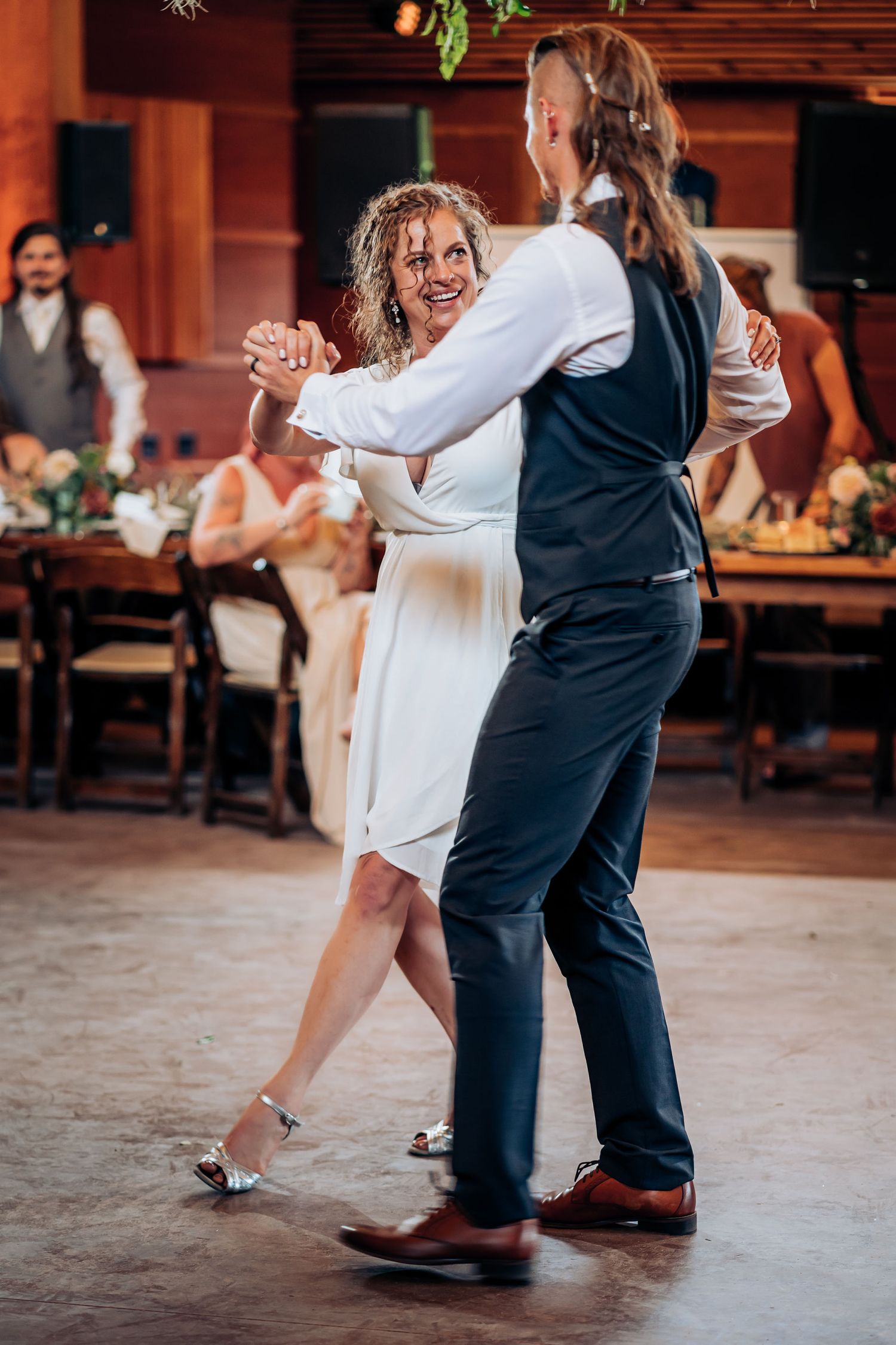 Dancers share a joyful moment during a reception dance on a wooden floor.