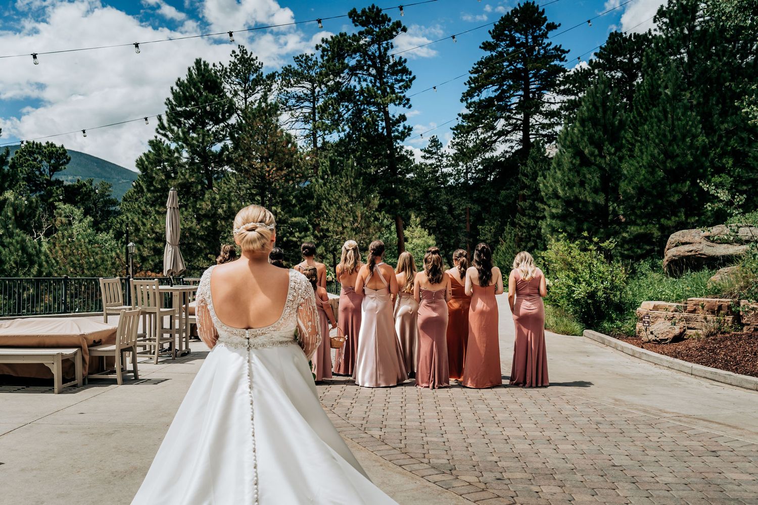 Wedding party gathered on a stone patio with mountain views and pink bridesmaid dresses.