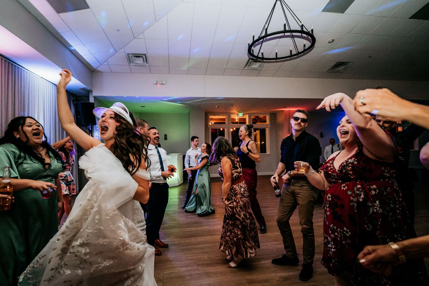Bride laughing and dancing with wedding guests in a joyful reception celebration.