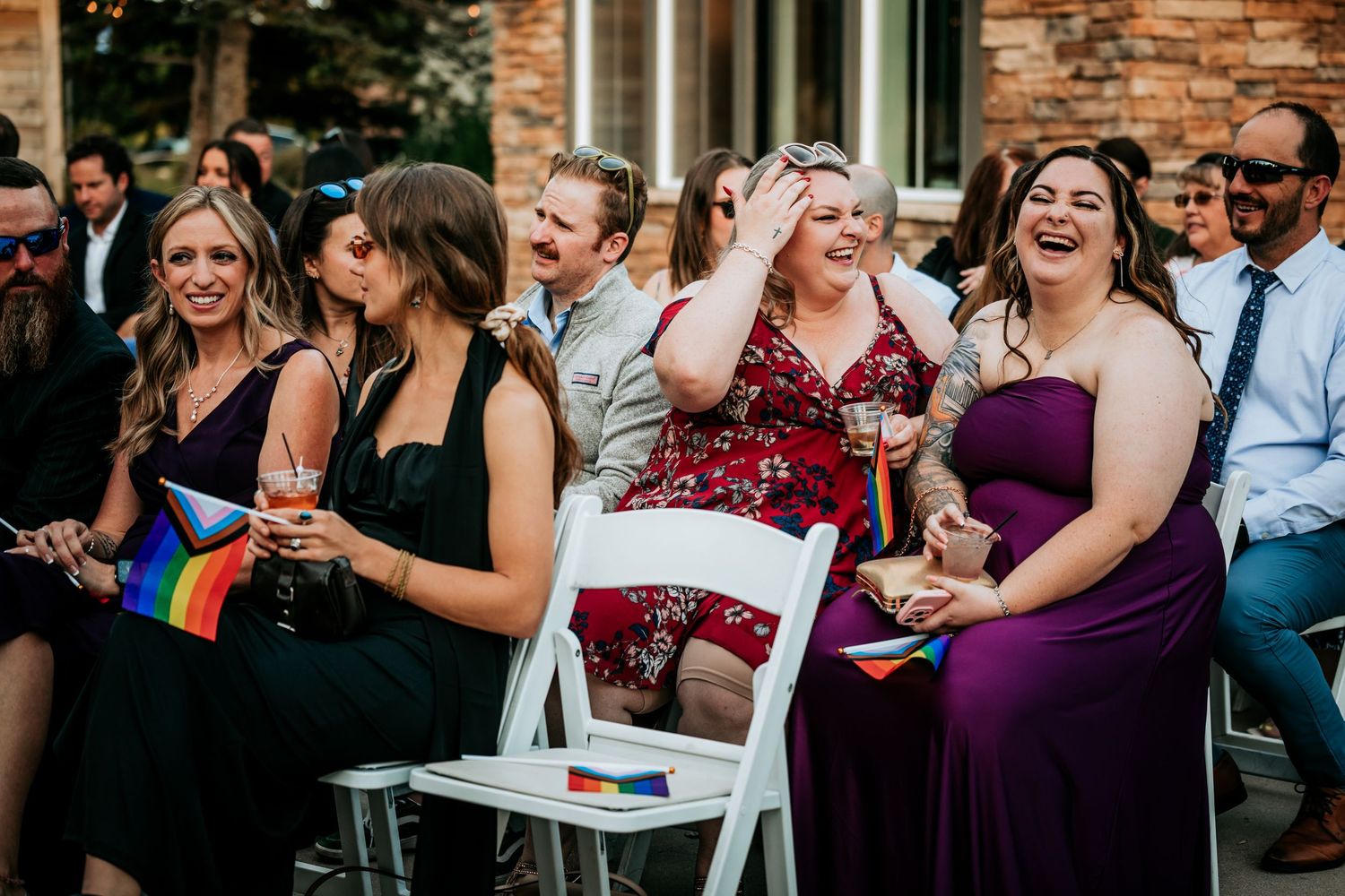 Happy wedding guests laugh and celebrate during outdoor wedding ceremony reception.