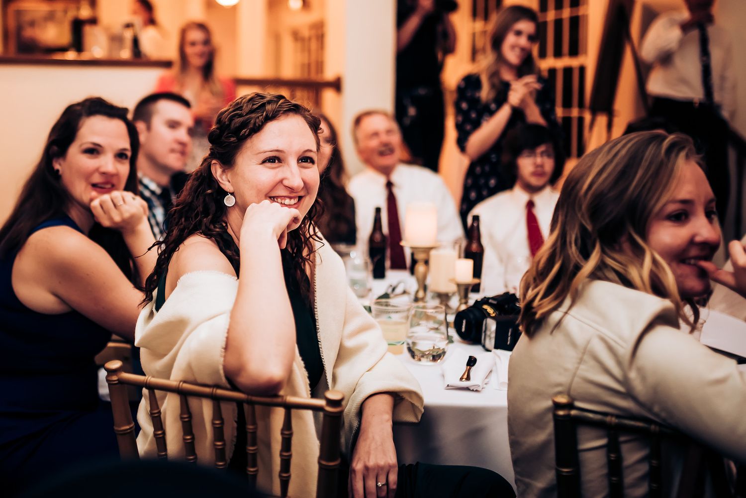 Wedding guests enjoying themselves at elegant reception tables with soft lighting.