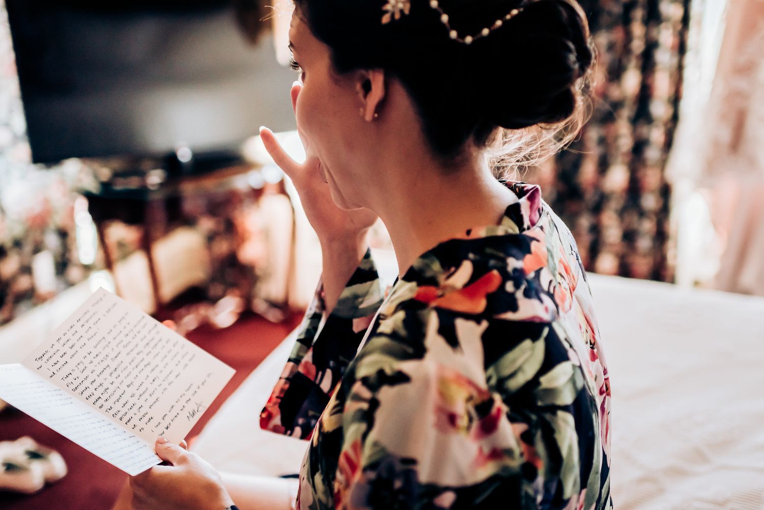 Person in floral robe reading document in warm lighting.
