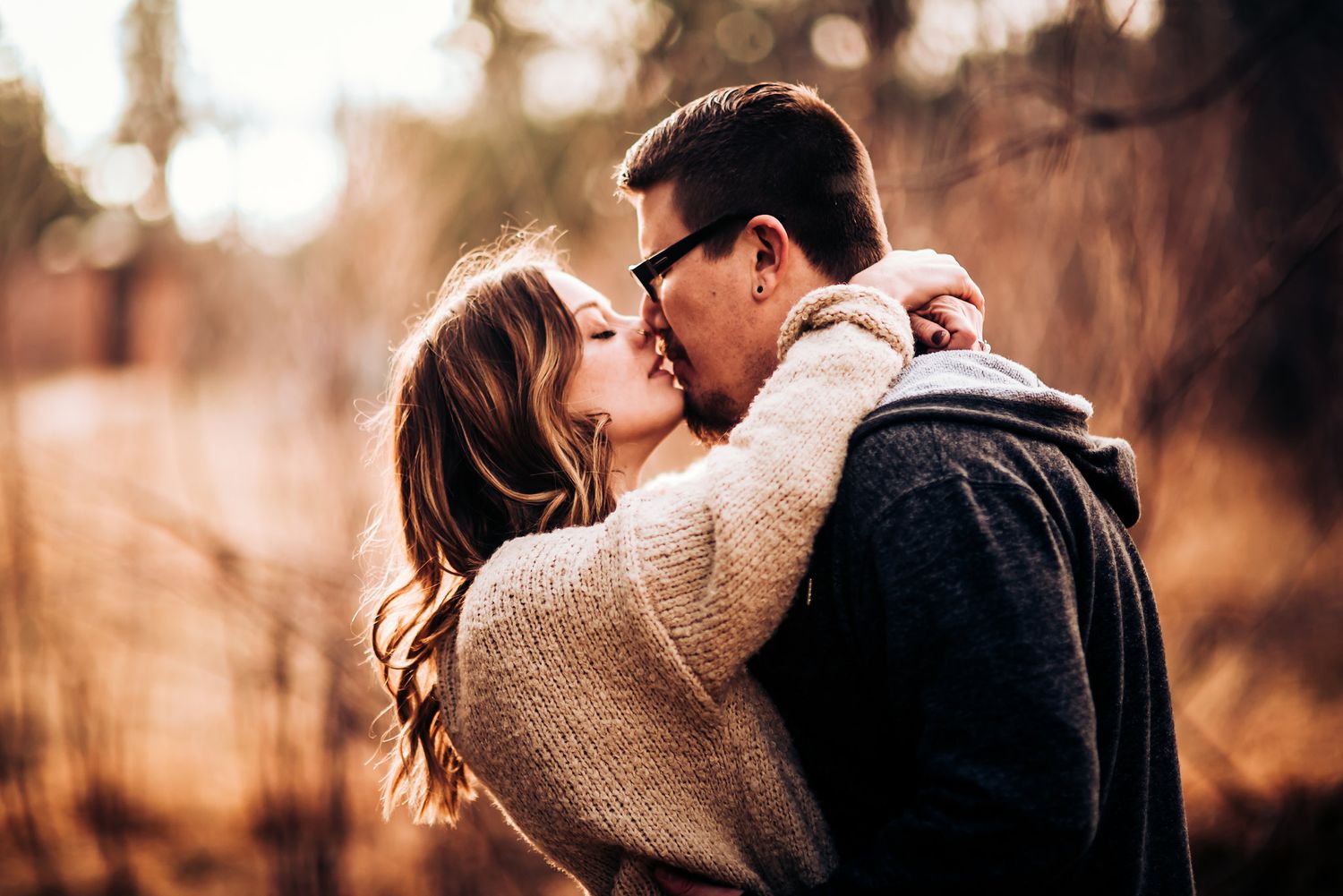 Intimate autumn portrait of couple embracing outdoors in golden light.