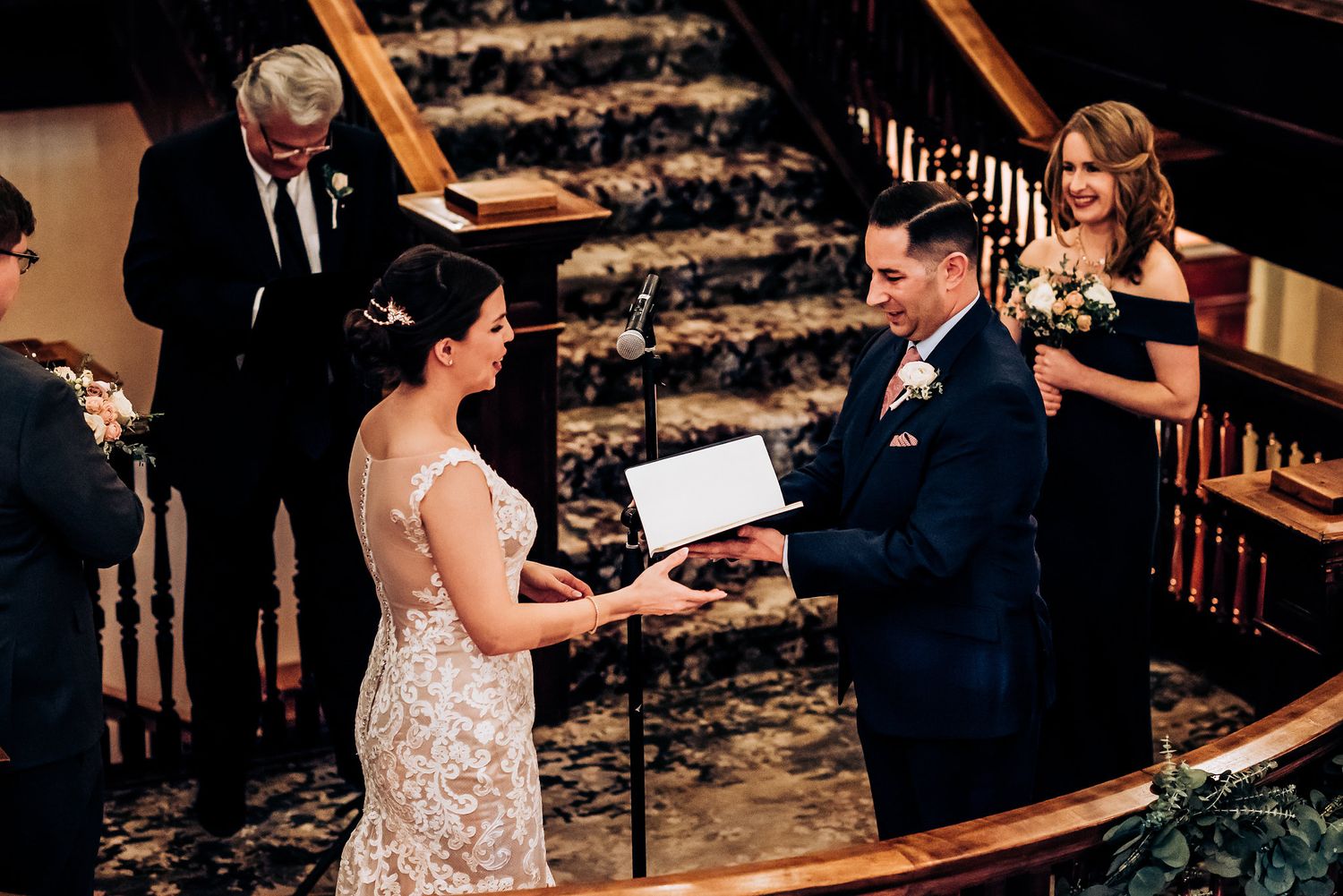 A traditional wedding ceremony takes place on a elegant wooden staircase with decorative railings.