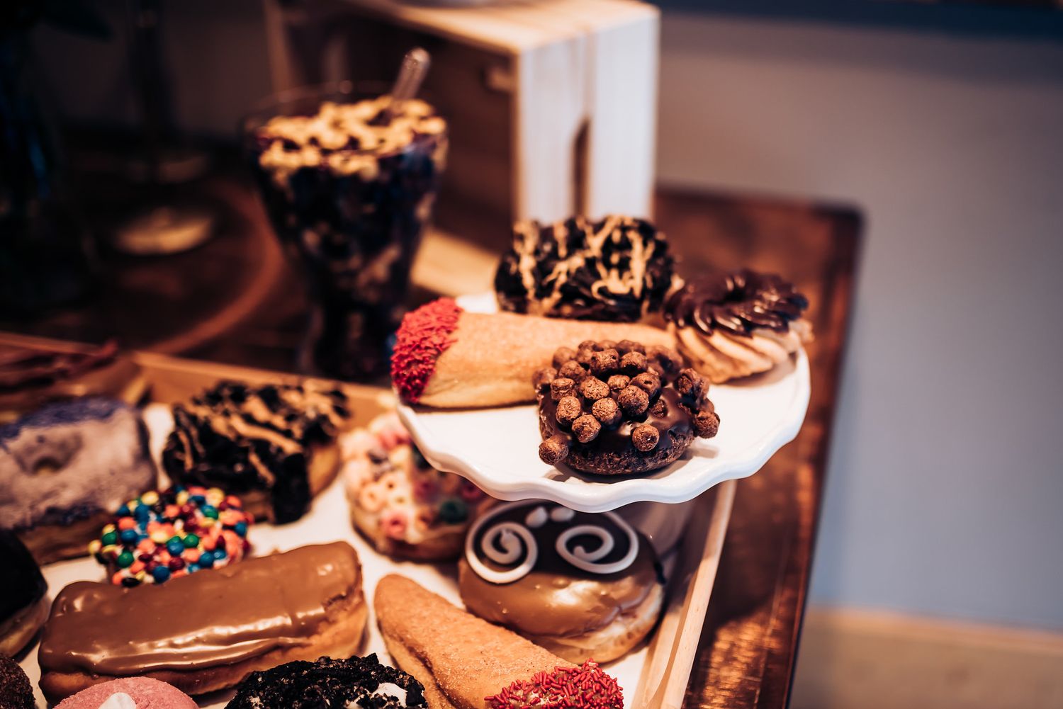 Variety of chocolate covered desserts and pastries displayed on tiered white stands.