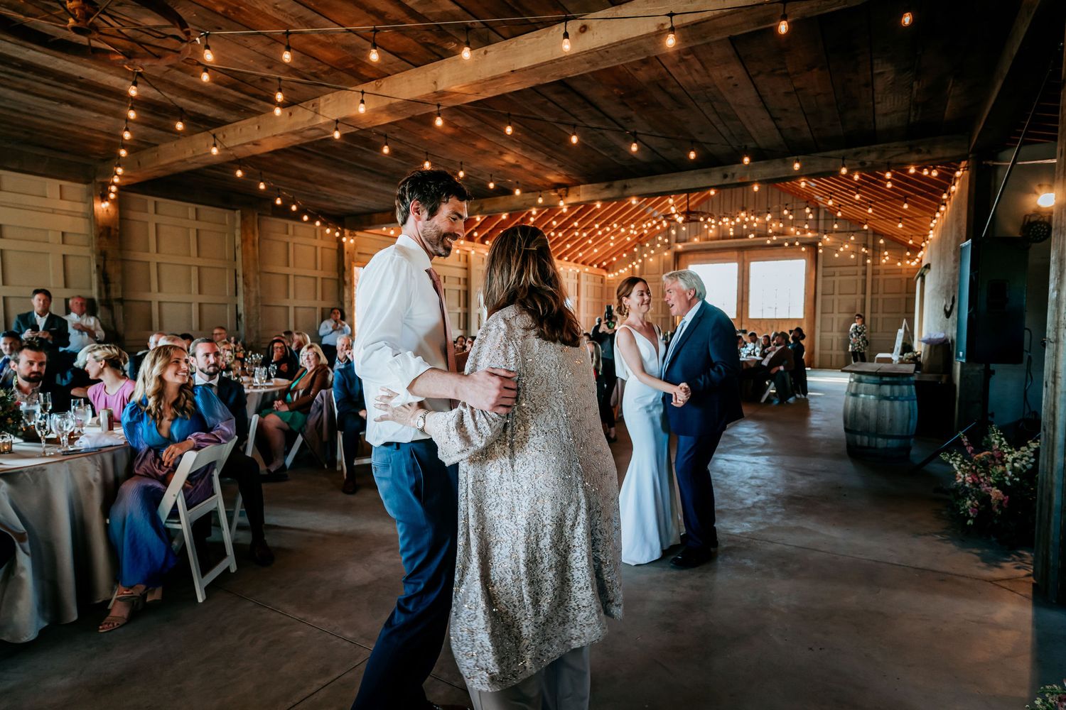 Wedding reception dance floor with twinkle lights decorating the rustic venue ceiling.