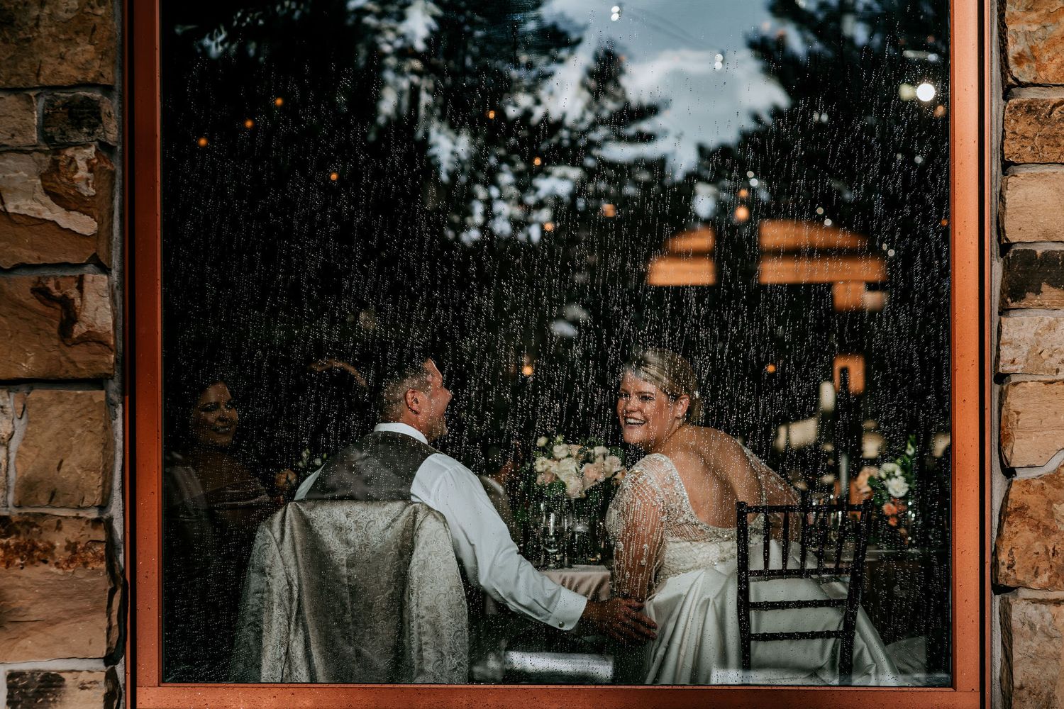 Wedding couple sharing an intimate moment through a window frame with stone walls.