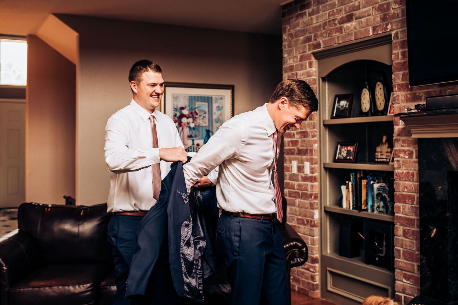 Two men helping each other get dressed in formal attire.