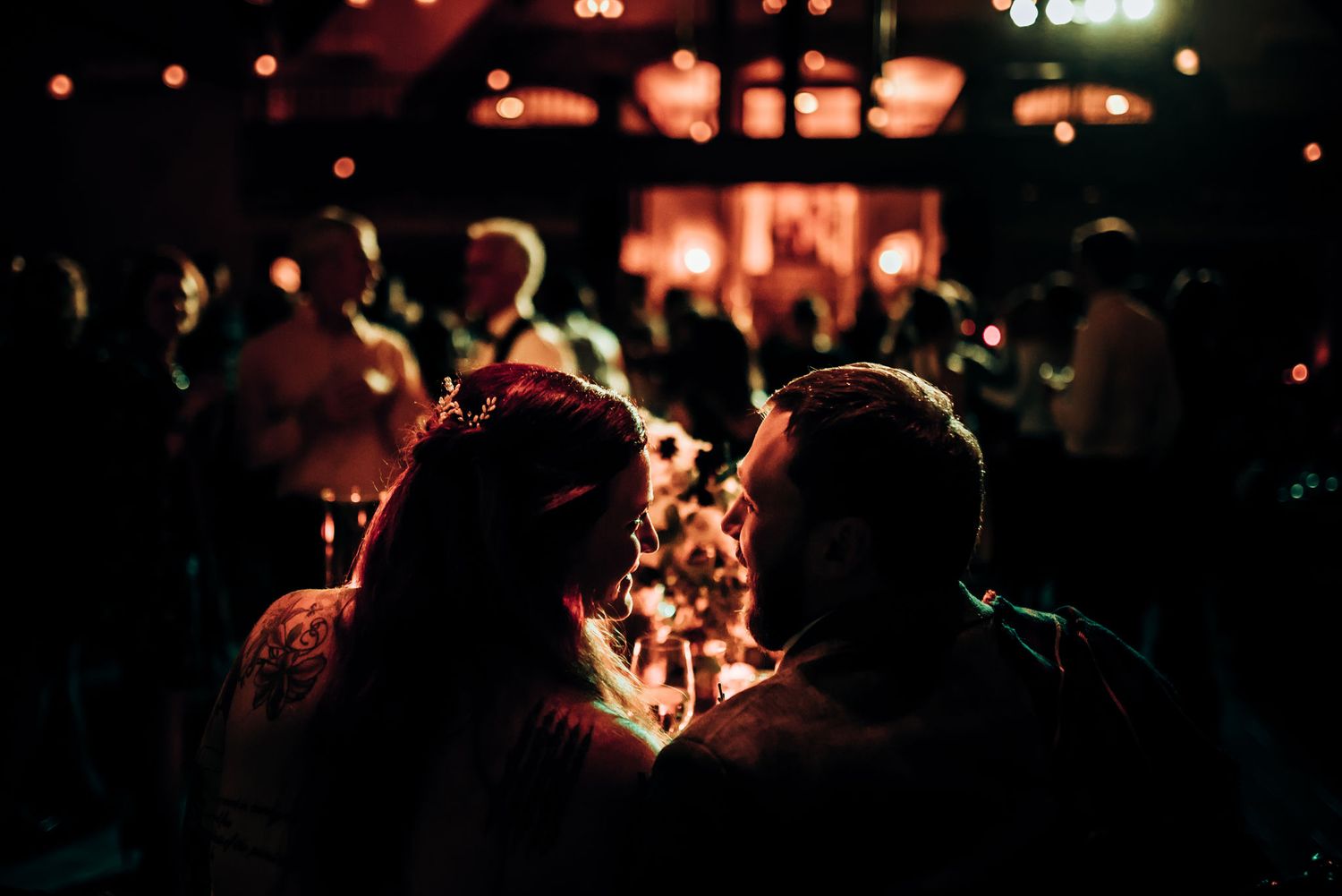 Romantic silhouette of a couple against warm lighting and bokeh at an evening event.