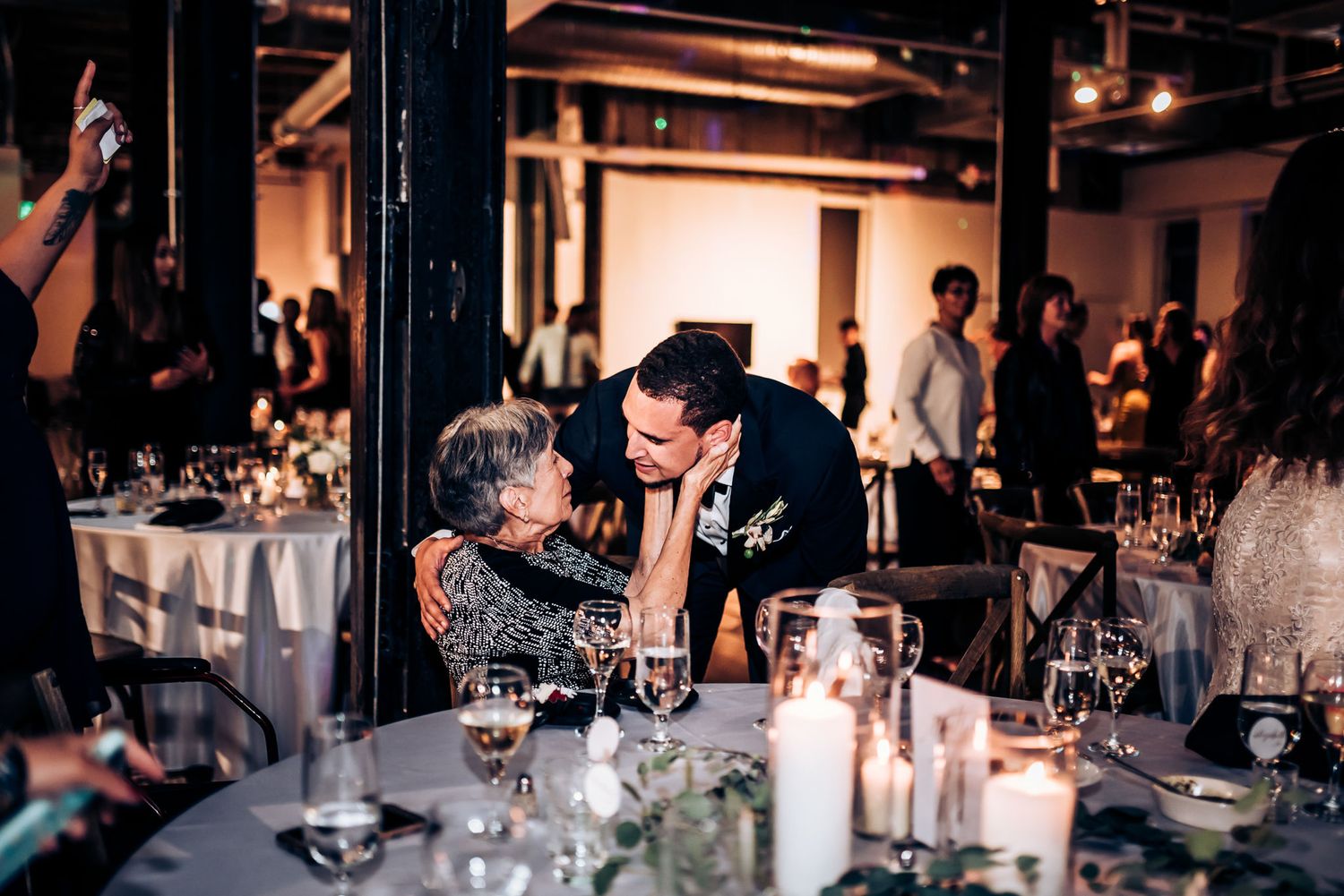 A touching moment shared between guests during a candlelit wedding reception dinner.