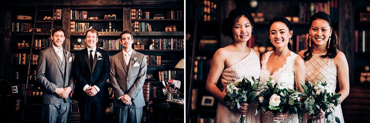 Wedding party poses together in elegant library setting with dark wooden bookshelves.