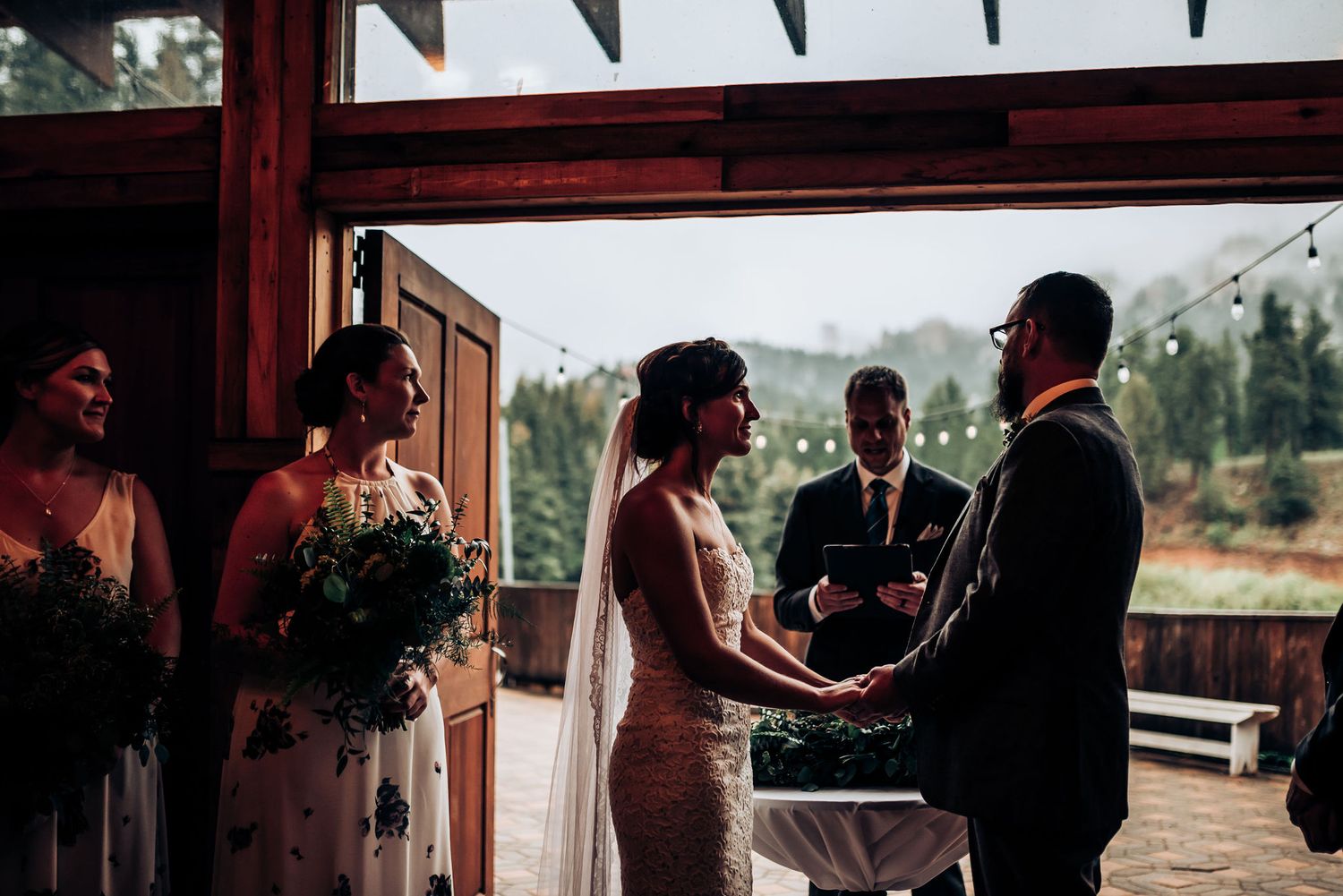Wedding ceremony taking place in an outdoor covered venue with mountain views.