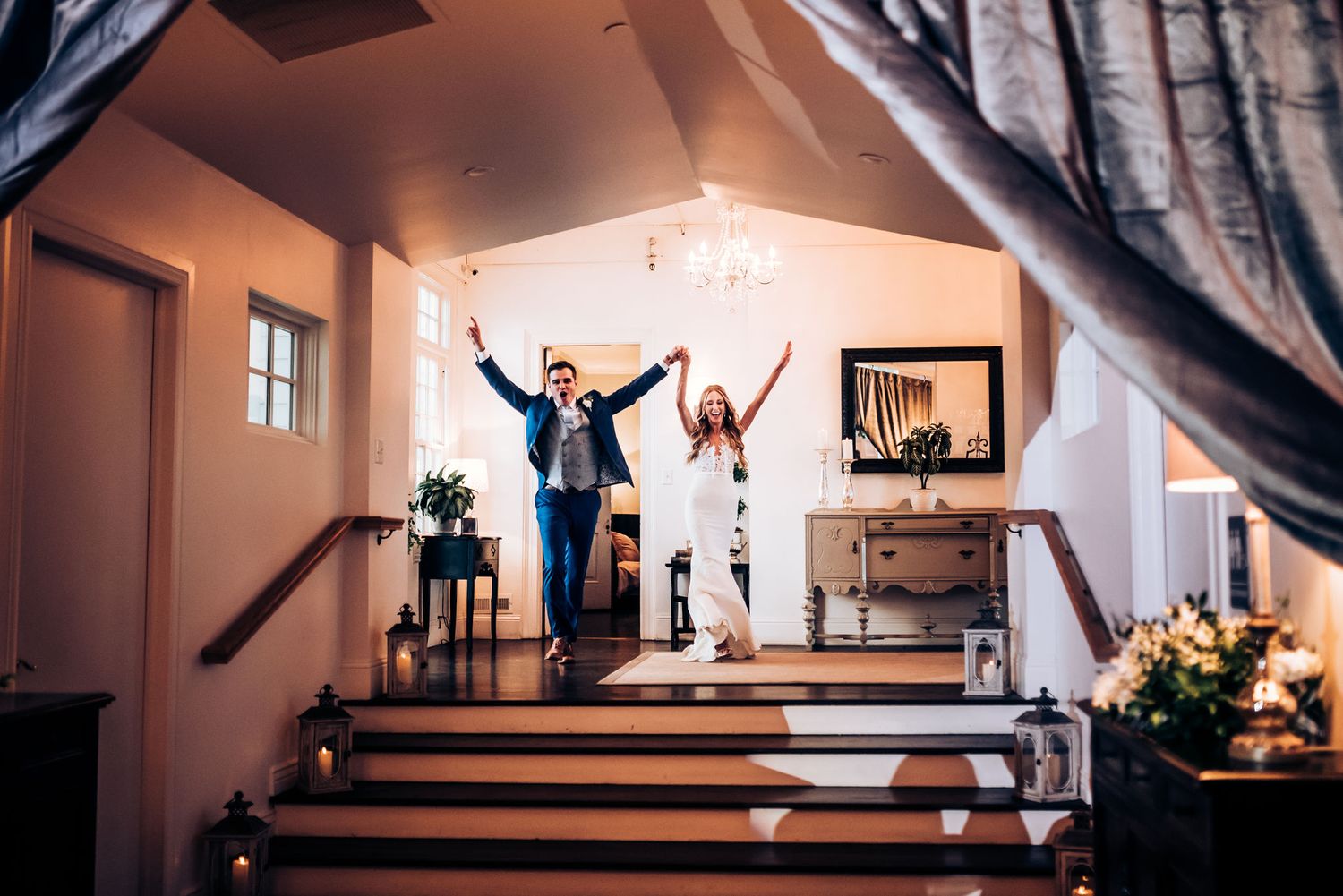 Celebratory moment on stairs at a wedding venue with raised arms.