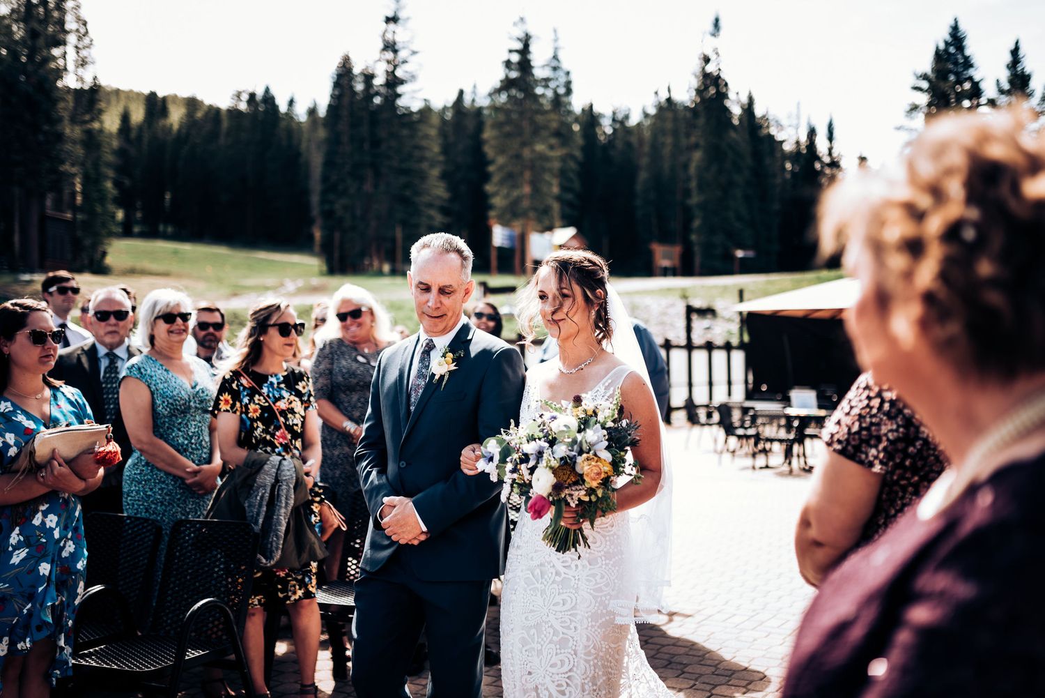 Outdoor mountain wedding ceremony with guests watching processional.