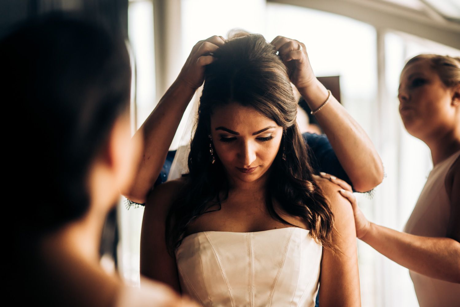 Someone in a white dress getting their hair styled in preparation for a special event.