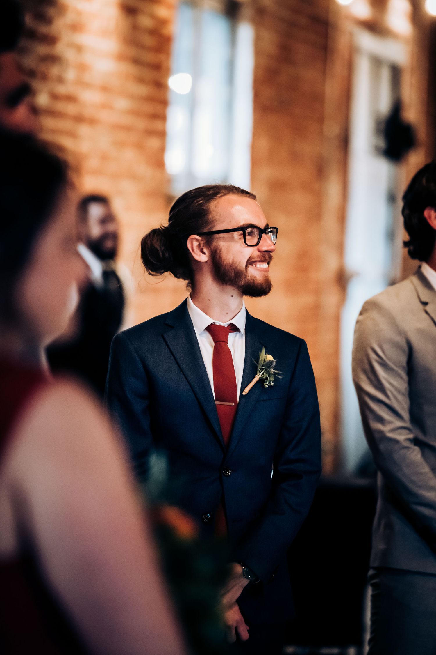 A candid moment during a wedding celebration in an elegant brick-walled venue.