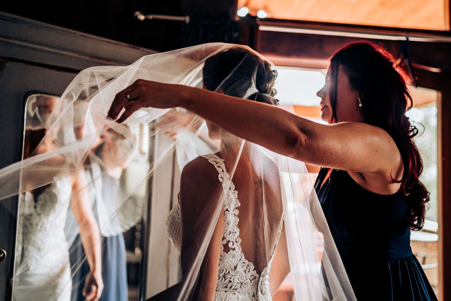 White wedding veil being adjusted in warm indoor lighting during bridal preparations.