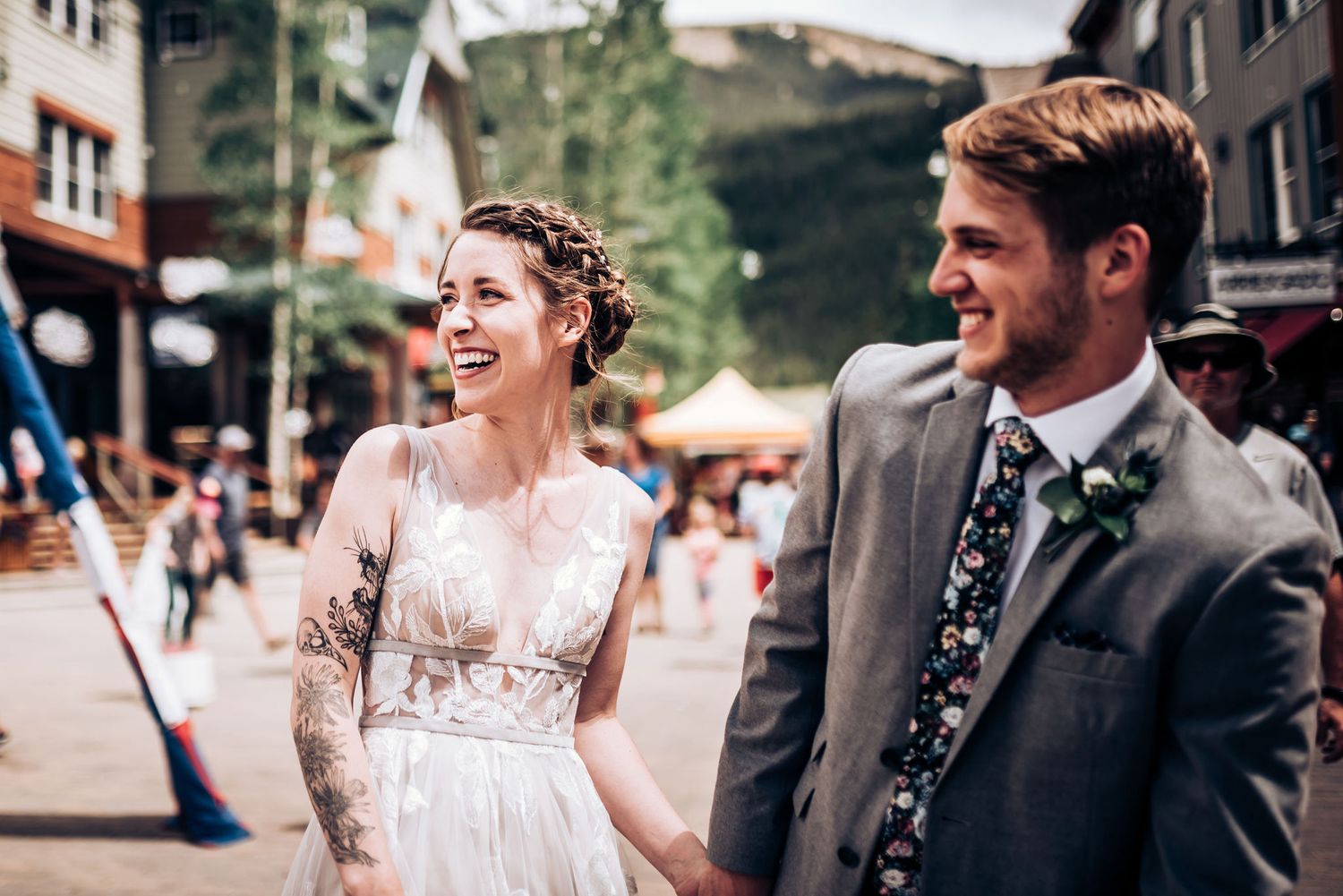 Happy couple strolls through bustling mountain village street during their wedding day.