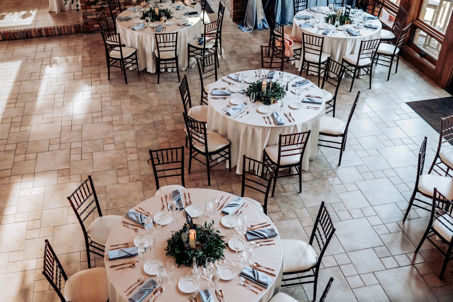 Elegant wedding reception setup with round tables, chiavari chairs, and centerpieces.