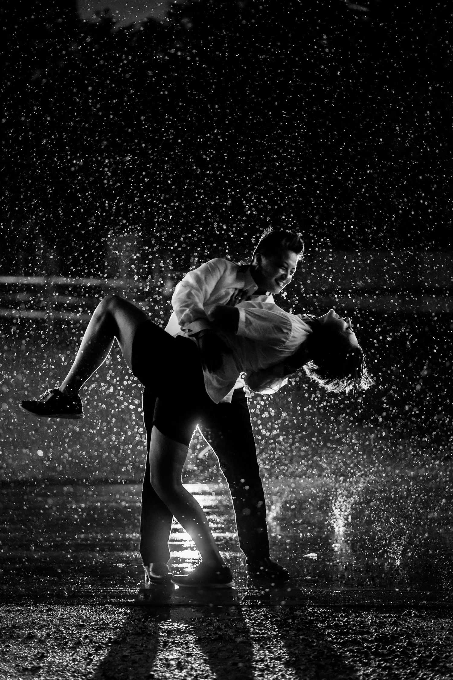 Dramatic black and white dance photo with water droplets creating a sparkling effect.