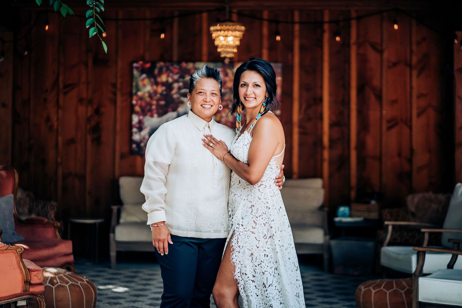 A romantic indoor celebration moment under a crystal chandelier in a rustic wooden venue.