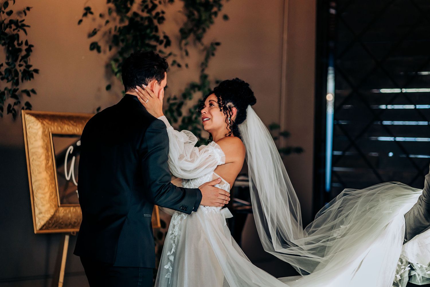 A romantic wedding couple shares an intimate dance moment in a dimly lit reception venue.
