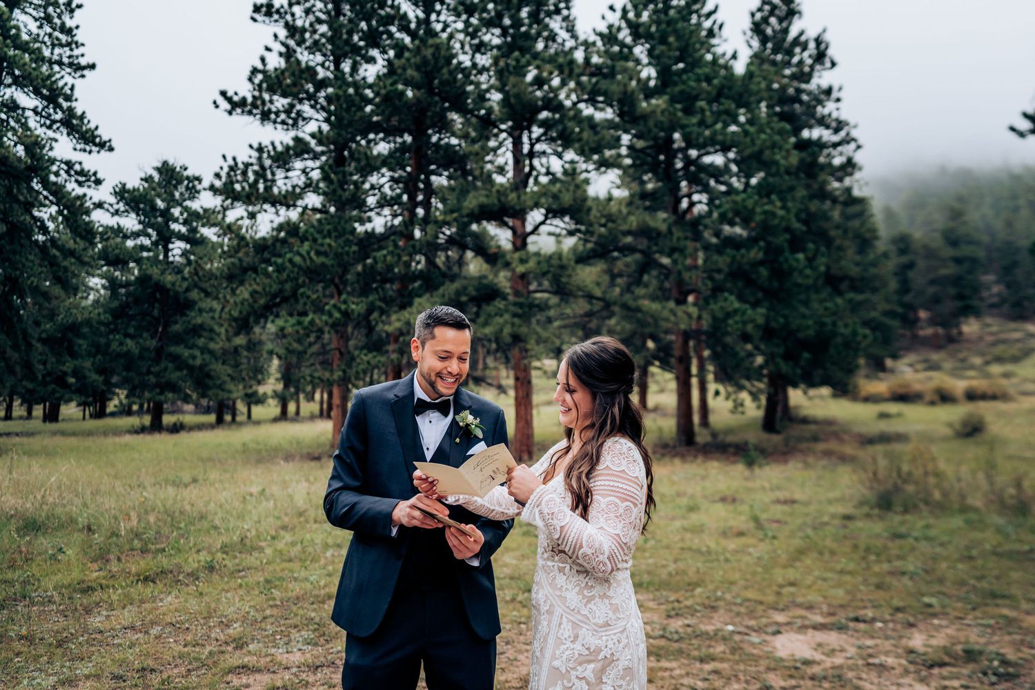 A couple in wedding attire exchanges vows in a serene mountain meadow.
