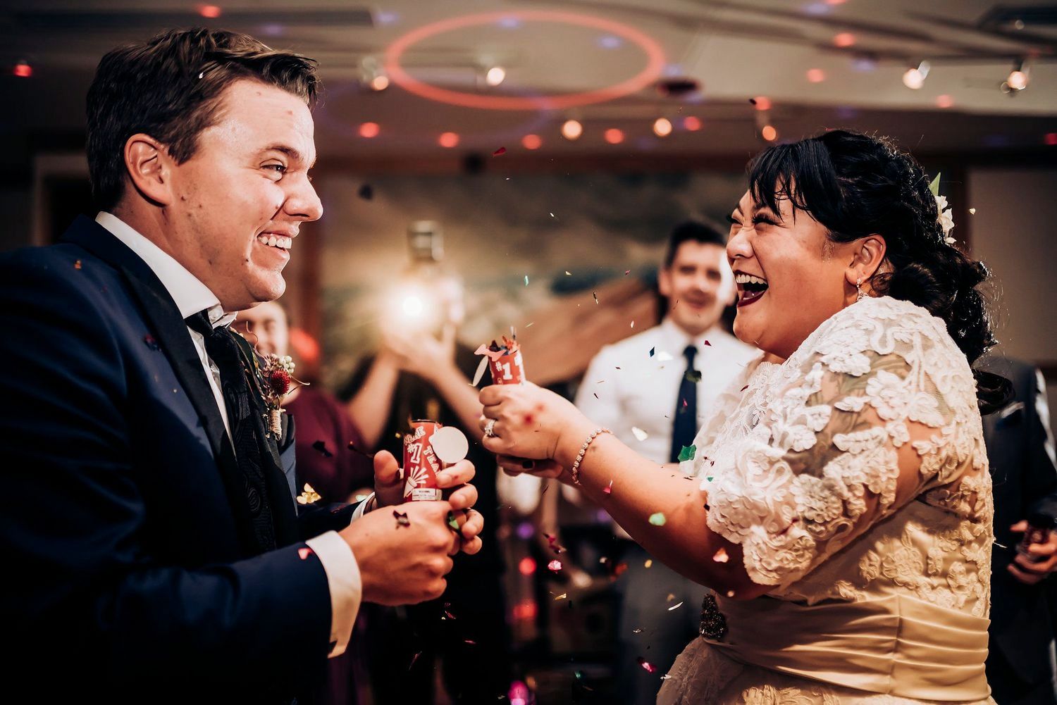 Couple shares joyful dance moves at a wedding reception with warm lighting and festive atmosphere.