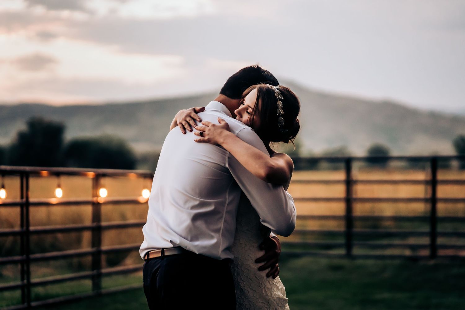A couple shares an intimate moment against a sunset mountain backdrop.