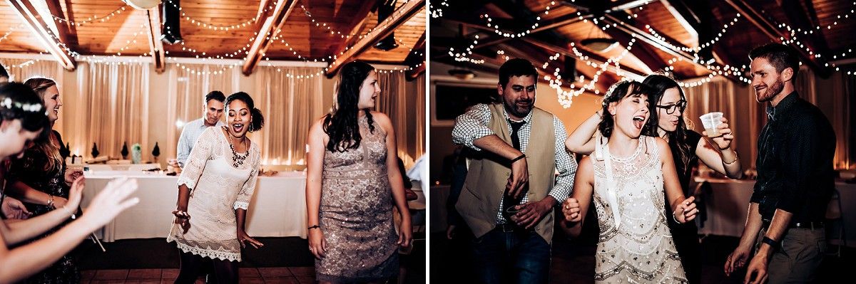 Wedding guests dance and celebrate in a rustic venue decorated with string lights.