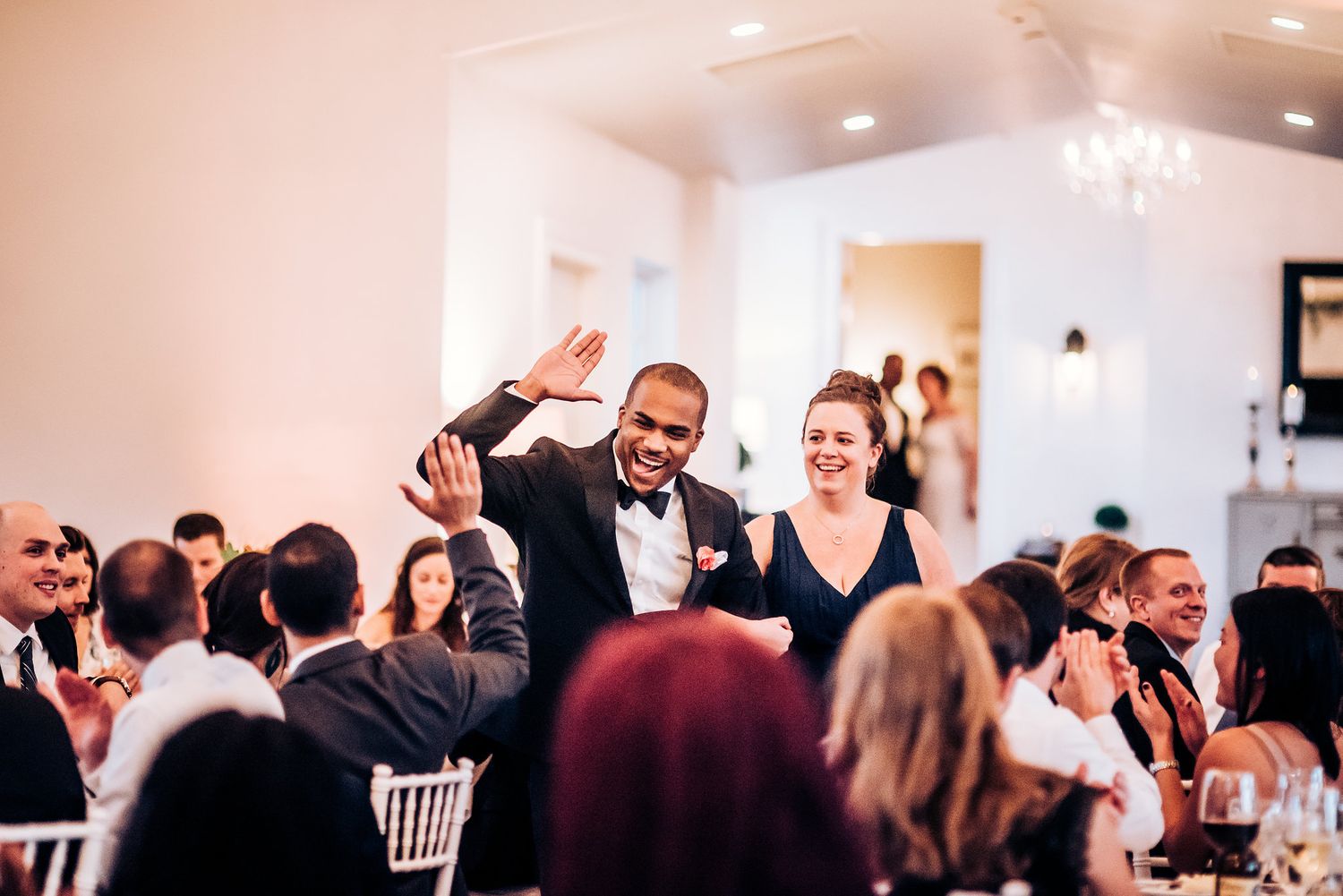 Joyful celebration moment captured during wedding reception with guests at decorated tables.