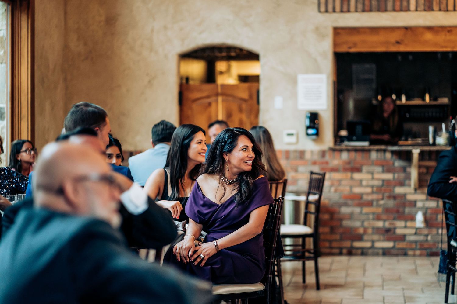 Guests enjoying themselves at an intimate wedding reception with brick walls.