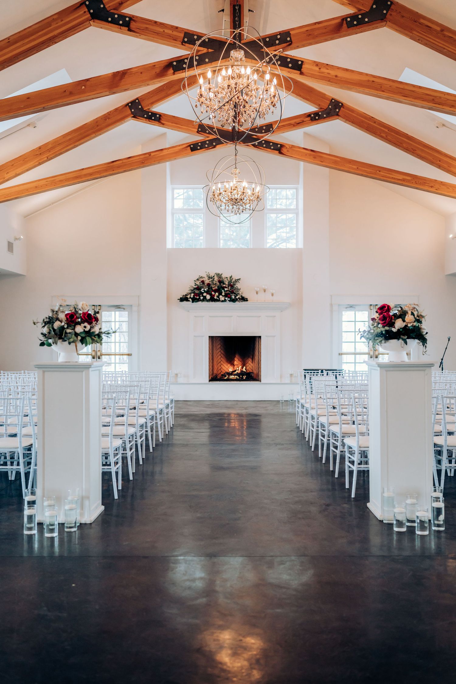 Elegant white wedding chapel interior with crystal chandeliers and wooden beam ceiling.