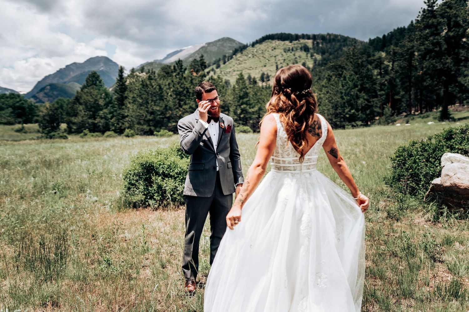 A romantic wedding moment captured in a mountain meadow with dramatic peaks in the background.