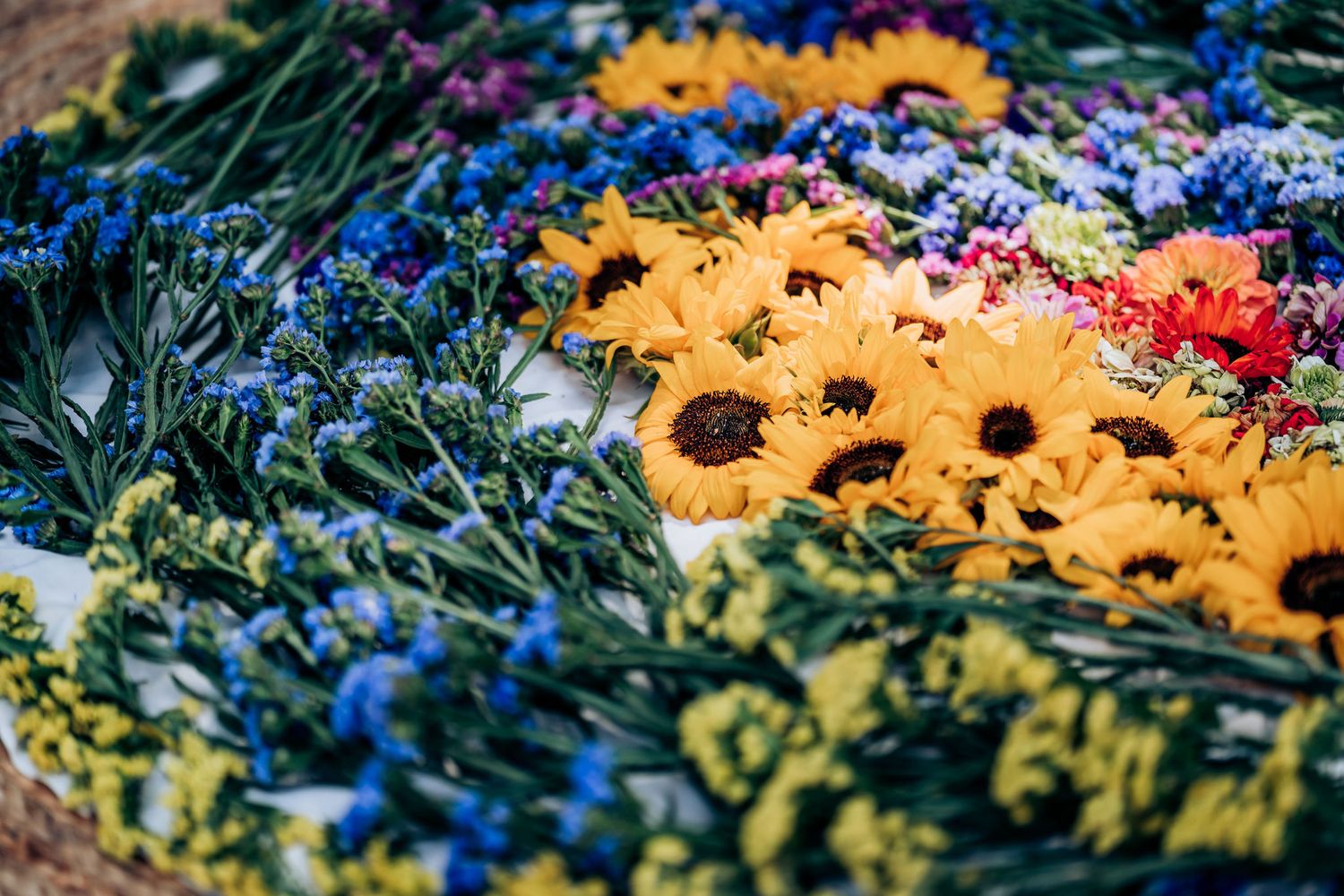 Close-up of a floral arrangement featuring bright sunflowers and blue delphinium flowers.
