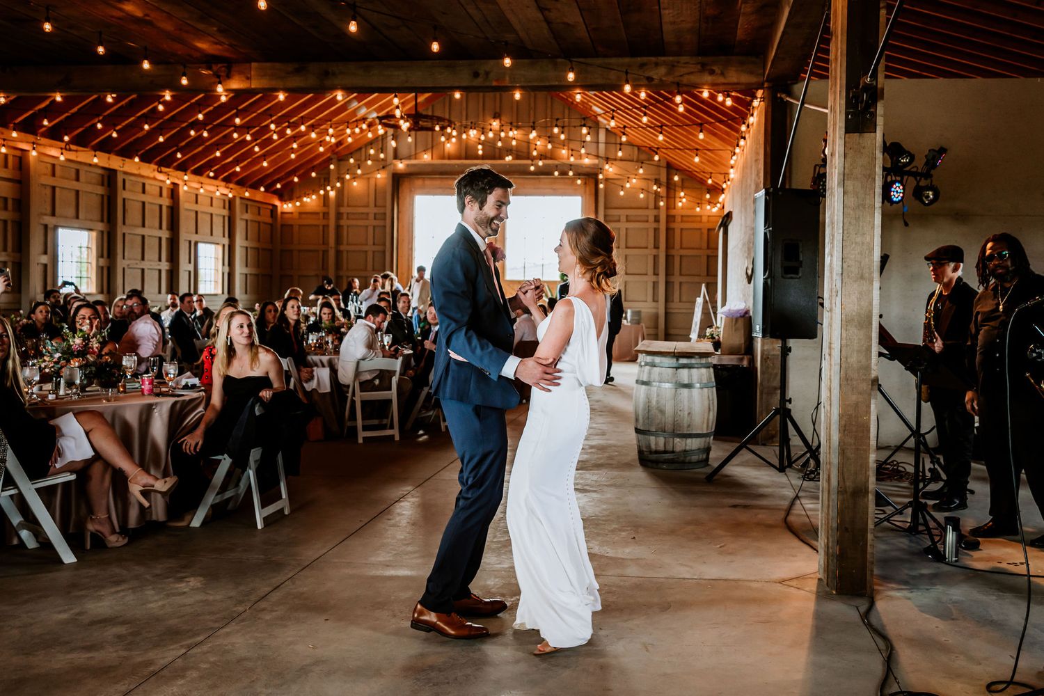 Wedding couple dancing together in an industrial venue decorated with string lights.